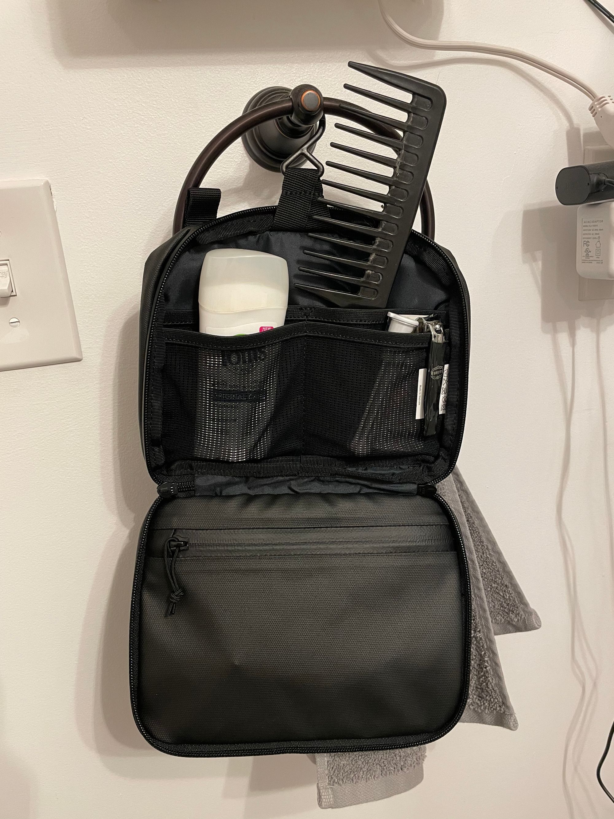 A small toiletry bag hangs on a hook. Deodorant and a comb are visible. 