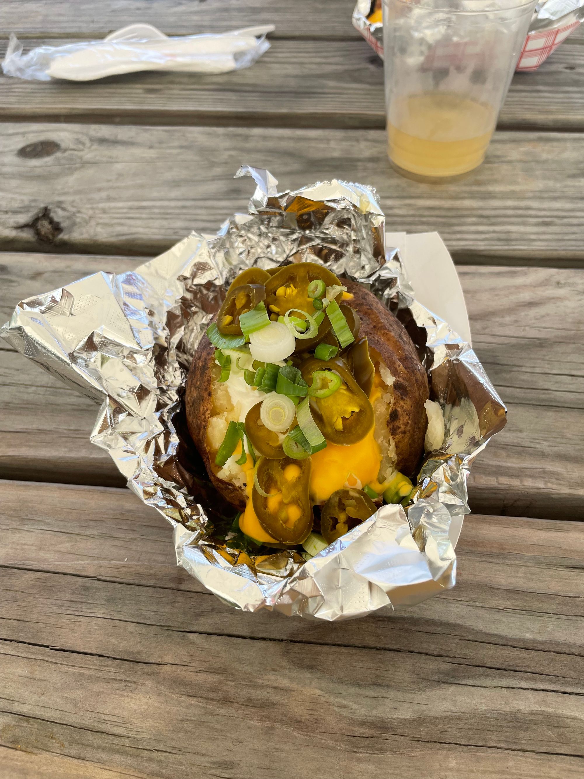 A baked potato with liquid cheese, jalapeños, sour cream, and chives.