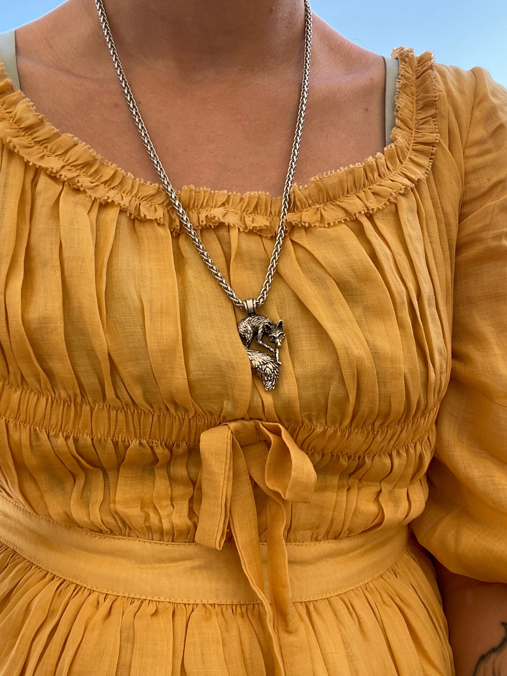 Closeup of a silver fox necklace being worn by a woman with a yellow dress.