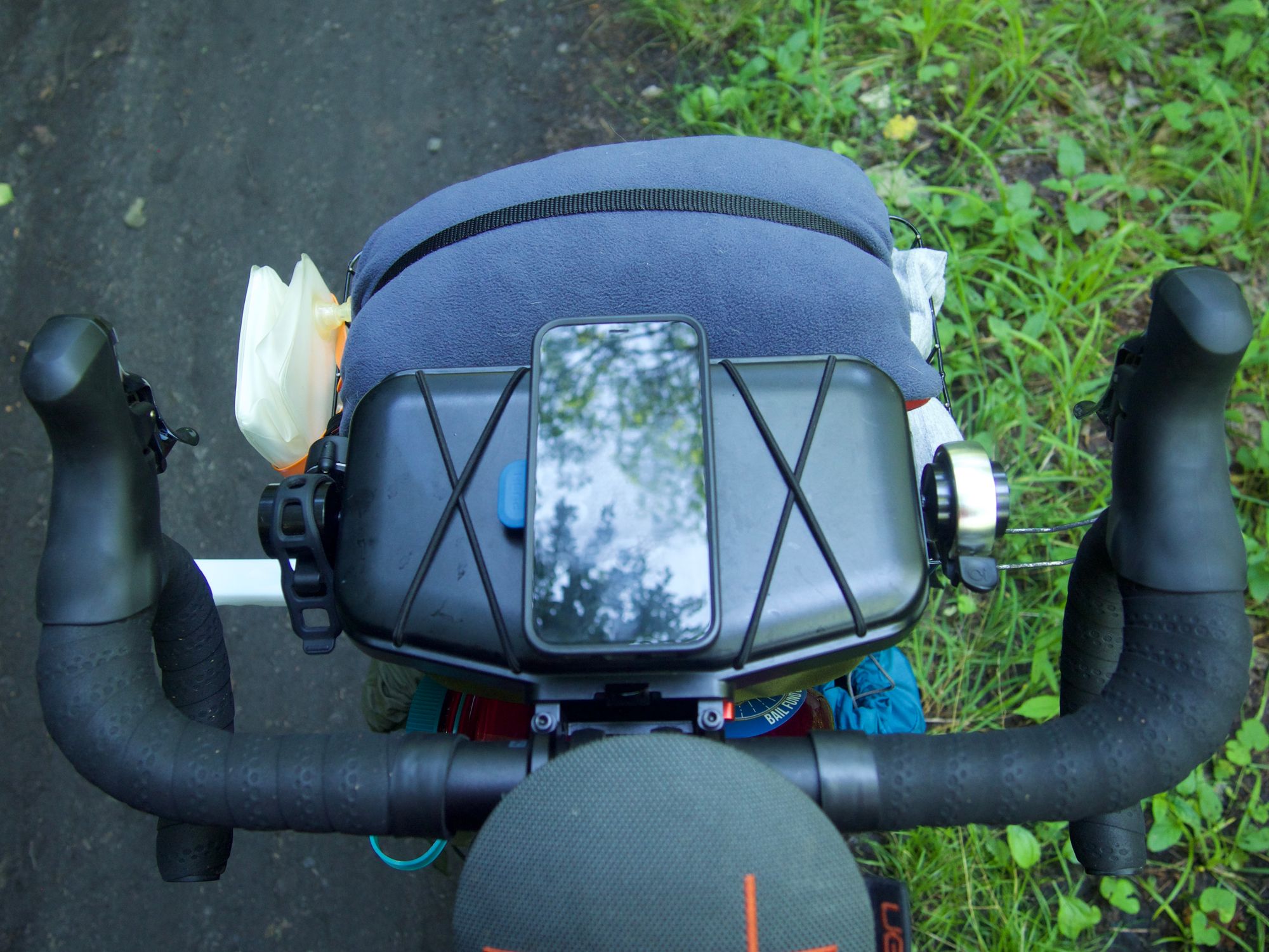 POV: handlebars. There's a phone and pillow strapped out front, along with a bluetooth speaker, bell, and headlight.