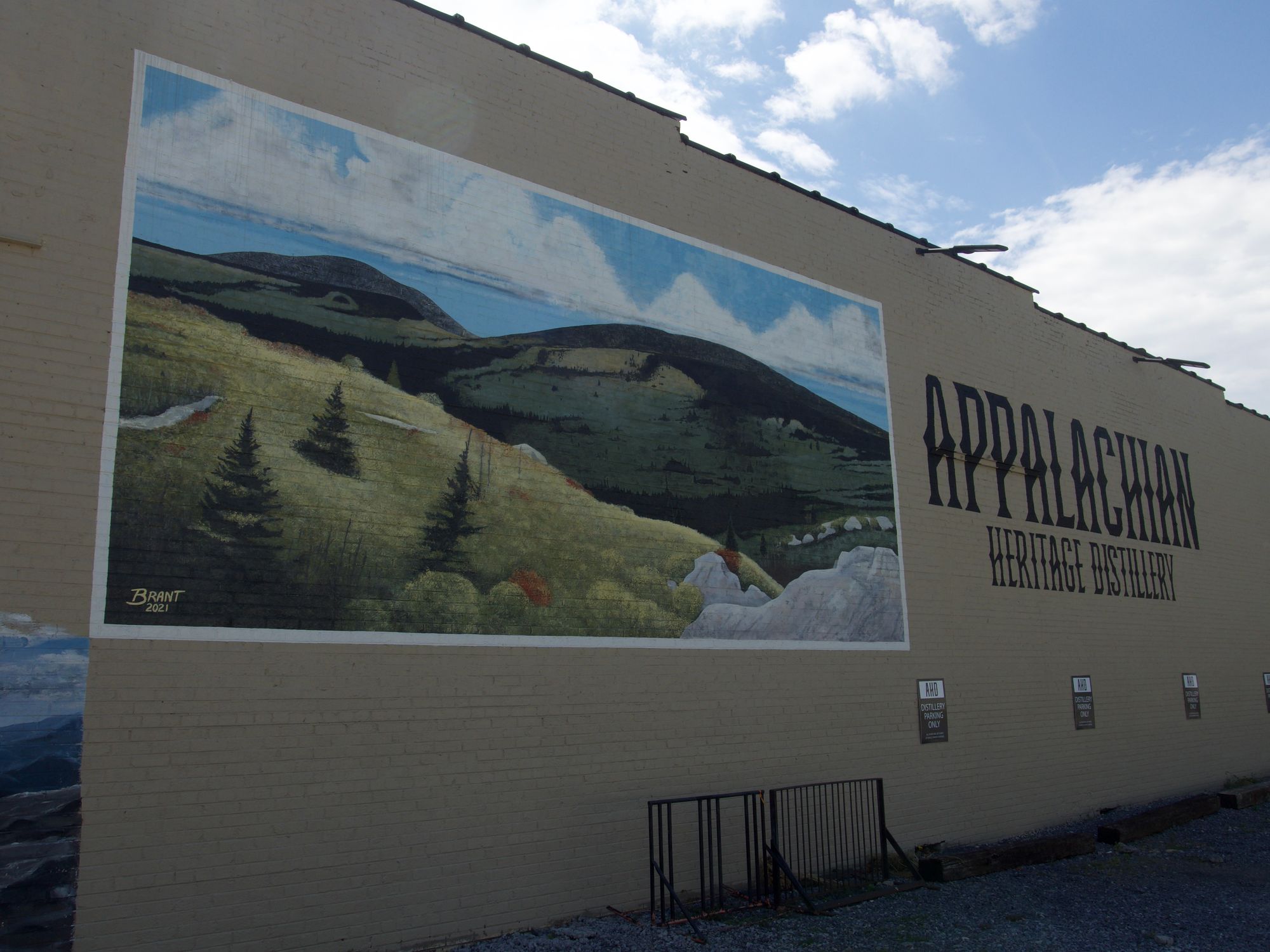 Mural of the mountains on a tan building. Lettering next to it reads: Appalachian Heritage Distillery.