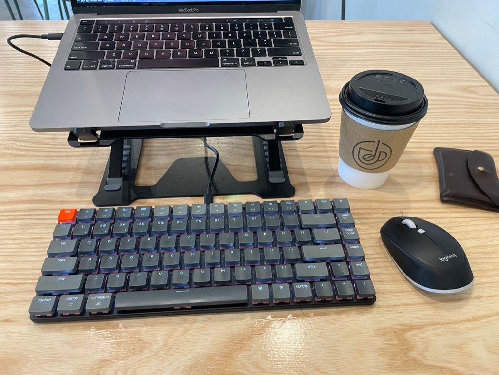 Laptop, keyboard, mouse, coffee cup, and wallet.